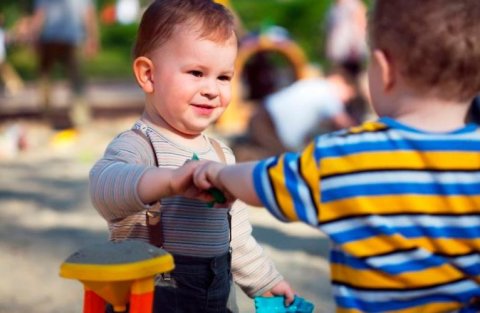 Мальчики делятся игрушками друг с другом на детской площадке